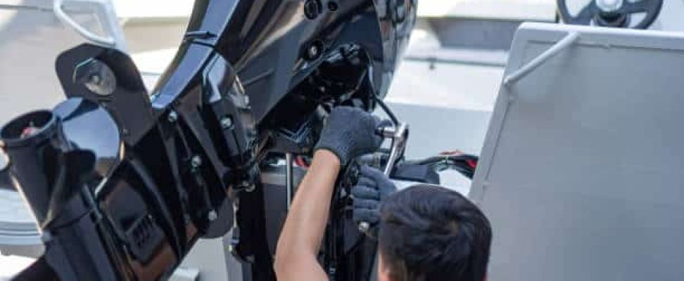 mechanic is installing speed boat engine , a new engine on an aluminum boat.